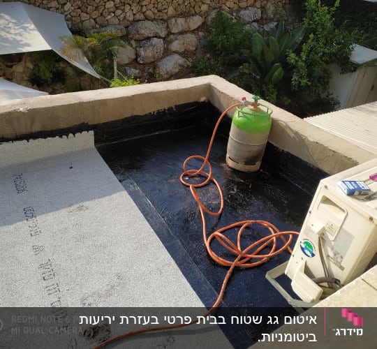 יריעה ביטומנית על גג עם בלון גז וצינור כתום